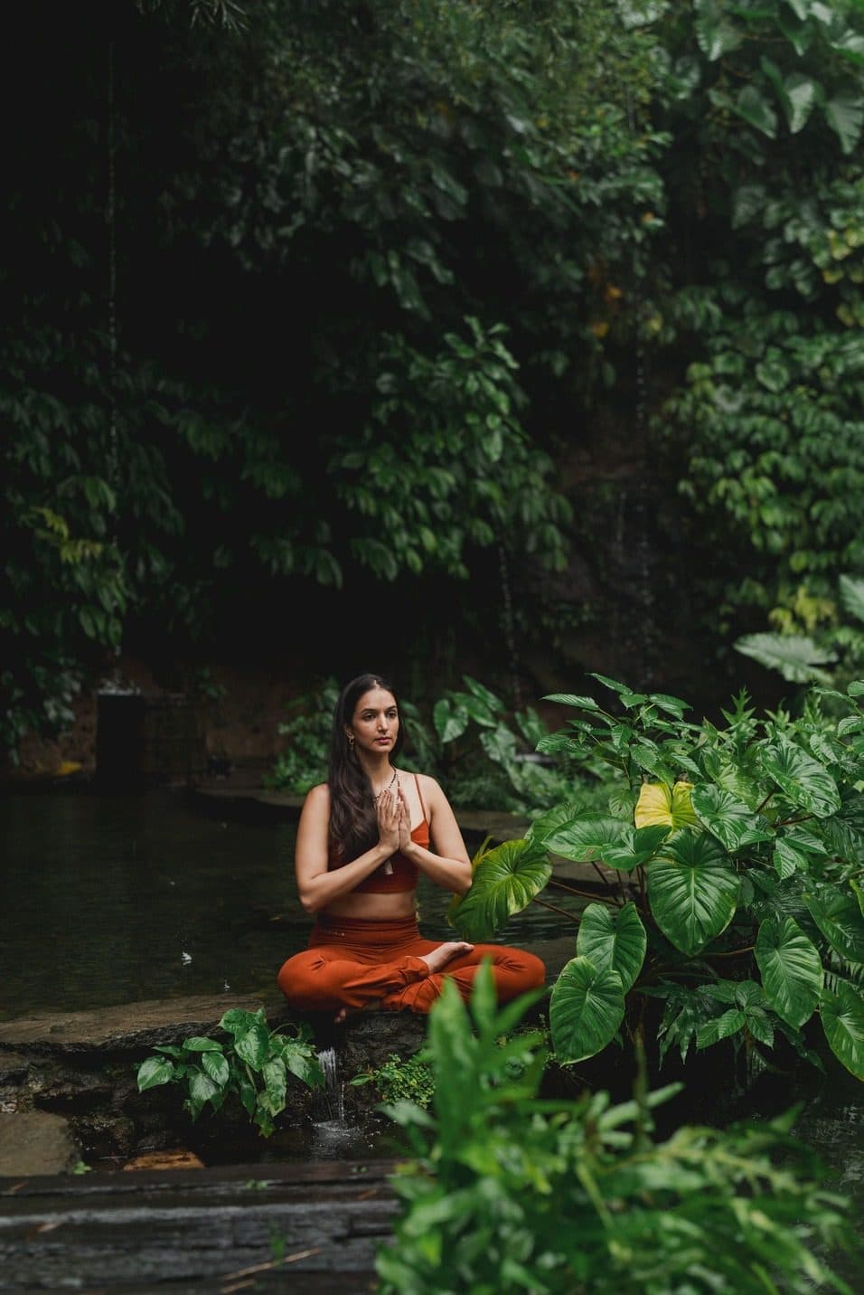 Ira Trivedi seated in meditation beside a forest pool
